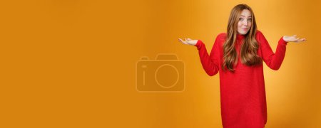 Téléchargez les photos : Que sais-je ? Portrait d'une femme rousse tendre et douce, désorientée, en pull rouge, haussant les mains près des épaules, se retournant, interrogée et ignorant, ne sachant pas. - en image libre de droit
