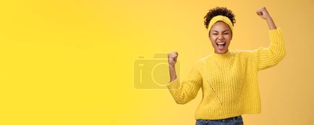 Foto de Activo saliente confiado alegre africano-americano hembra fan lugar apuesta esperanzadamente gritando animar equipo ganar de pie puños levantados victoria celebrando gesto gritando orgullosamente, amarillo fondo. - Imagen libre de derechos