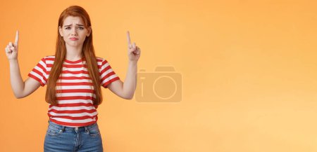 Photo for Disappointed upset cute whining timid redhead girl, gloomy face, pulling sad expression, complain, crying feeling regret loss, losing lottery, pointing up displeased, show despair and sorrow emotion. - Royalty Free Image