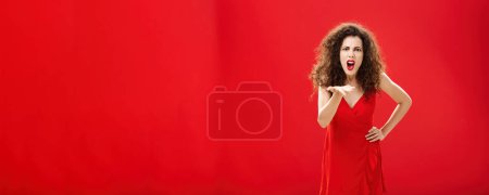 Photo for How dare you betray me. Pissed outraged bossy and displeased european adult woman with curly hairstyle in elegant dress bending towards camera with raised palm, complaining blaming and judging. - Royalty Free Image
