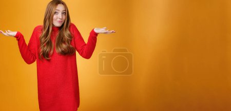 Photo for What do I know. Portrait of confused clueless tender and gentle redhead woman in red sweater shrugging with hands raised near shoulders turning away questioned and unaware, not knowing. - Royalty Free Image