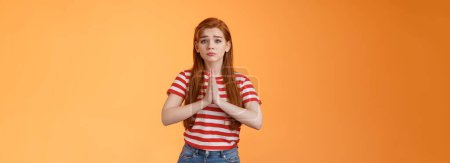 Photo for Silly redhead innocent girl acting pity, pulling sad face begging for help, hold hands pray, frowning, purse lips upset, plead favor, apologizing, saying sorry, stand orange background in need. - Royalty Free Image
