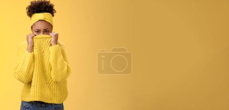 Photo for Cute upset scared timid insecure african-american offended girl hiding face pulling sweater collar nose frowning pouting look sorrow insulted afraid watching scary horror movie alone, need support. - Royalty Free Image