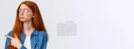 Photo for Close-up portrait gloomy and sad pouting cute redhead girl with lovely blue eyes, wear glasses, sulking and sobbing sad, pointing looking upper left corner with regret or jealousy, want something. - Royalty Free Image