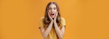Photo for Lifestyle. Waist-up shot of surprised and amused girl learning shocking awesome rumor touching cheeks from amazement opening mouth intrigued gazing at camera focused on interesting story over orange - Royalty Free Image
