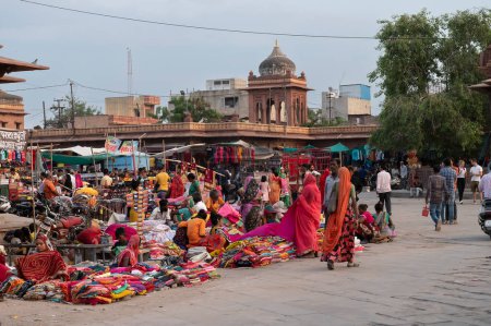 Photo for Jodhpur, Rajasthan, India - 20.10.2019 : Rajasthani womens clothes being sold at Famous Sardar Market and Ghanta ghar Clock tower in the evening. - Royalty Free Image