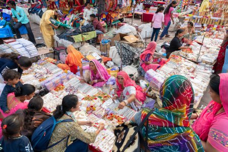 Téléchargez les photos : Jodhpur, Rajasthan, Inde - 20.10.2019 : Des colliers blancs, des boucles d'oreilles plaquées or et des ornements sont vendus à de jeunes clientes au célèbre marché Sardar et à la tour de l'horloge ghar Ghanta à Jodhpur. - en image libre de droit
