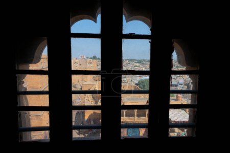 Téléchargez les photos : Jaisalmer, Rajasthan, Inde - 15 octobre 2019 : Vue de la ville de Jaisalmer à travers le grès fait beau jharokha, fenêtre en pierre. Intérieur de Rani Mahal ou Rani Ka Mahal, à l'intérieur du fort de Jaisalmer. - en image libre de droit