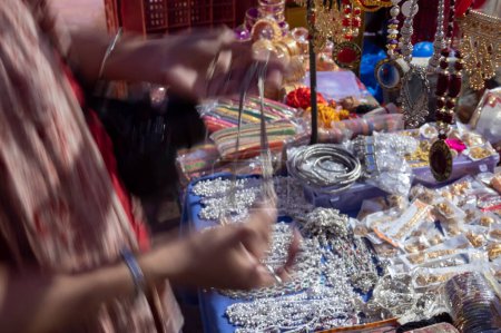 Téléchargez les photos : Femme indienne essayant colliers blancs et boucles d'oreilles plaqué or sont vendus au célèbre marché de Sardar et Ghanta ghar tour de l'horloge à Jodhpur, Rajasthan, Inde. - en image libre de droit