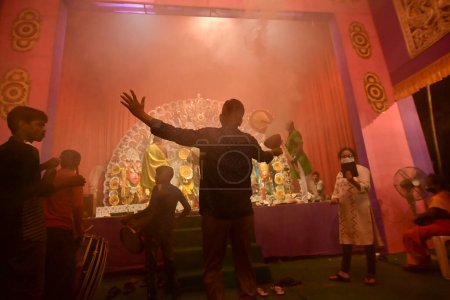 Foto de Howrah, Bengala Occidental, India - 13 de octubre de 2021: devoto hindú bailando dhunuchi naach, frente a la Diosa Durga como ritual, mientras que dhaakis jugando dhaaks. Santo humo cubrió toda el área. - Imagen libre de derechos