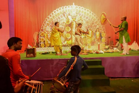 Téléchargez les photos : Howrah, Inde - 13 octobre 2021 : Les Dhaakis jouent aux dhaaks tandis que les prêtres hindous adorent la déesse Durga avec panchapradip, chamor et ventilateur à main. Ashtami puja aarati - rituel sacré de Durga Puja. - en image libre de droit