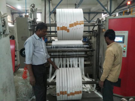 Téléchargez les photos : Kolkata, West Bengal, India - 6th May 2021 : White Paper Reels are being slitted from bid roll before being used as bottom of Paper cups. Indian paper cup making industry is growing. - en image libre de droit