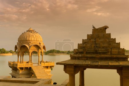 Téléchargez les photos : Chhatris and shrines of hindu Gods and goddesses at Gadisar lake, Jaisalmer, Rajasthan, India. Indo-Islamic architecture , sun set and colorful clouds in the sky with view of the Gadisar lake. - en image libre de droit