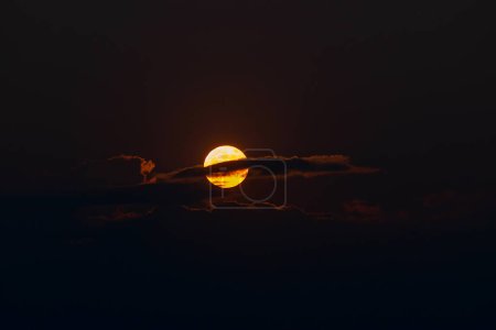 Photo for The orange moon, also known as the harvest moon or the hunter's moon, over the night sky at Sikkim, India. Moon is partly covered by clouds. - Royalty Free Image