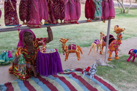 Photo for Jodhpur, Rajasthan, India - 19th October 2019 : Old aged Rajasthani woman selling hand made Rajaasthani colourful dolls of camels and horse. Rajasthan is famous for its vibrant colors all across. - Royalty Free Image