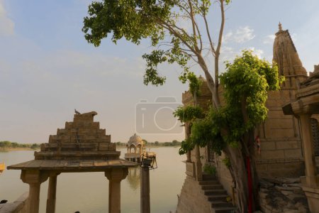 Foto de Chhatris and shrines of hindu Gods and goddesses at Gadisar lake, Jaisalmer, Rajasthan, India. Indo-Islamic architecture , sun set and colorful clouds in the sky with view of the Gadisar lake. - Imagen libre de derechos