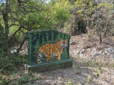 Photo for A tiger, Panthera tigris, on the sign board at Karnataka tiger reserve. The road goes through deep forest of the famous tiger reserve. Shot at forest of Karnataka, India. - Royalty Free Image