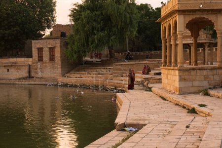 Foto de Jaisalmer, Rajastán, India - 13.10.2019: Chhatris y santuarios de dioses y diosas hindúes en el lago Gadisar. Arquitectura indoislámica con vista al lago Gadisar. - Imagen libre de derechos