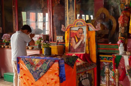 Photo for Sikkim, India - 22nd March 2004 : Devotee praying to Lord Buddha inside Buddhist Andey or Andhen monastery. Glass covered colorful Buddist Gods and Godesses, depicting earlier births of God Buddha. - Royalty Free Image