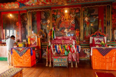 Foto de Sikkim, India - 22 de marzo de 2004: Devoto orando al Señor Buda dentro del monasterio budista de Andey o Andhen. Vidrio cubierto de coloridos dioses y diosas Buddistas, que representan nacimientos anteriores de Dios Buda. - Imagen libre de derechos