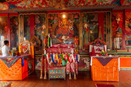 Photo for Sikkim, India - 22nd March 2004 : Devotee praying to Lord Buddha inside Buddhist Andey or Andhen monastery. Glass covered colorful Buddist Gods and Godesses, depicting earlier births of God Buddha. - Royalty Free Image
