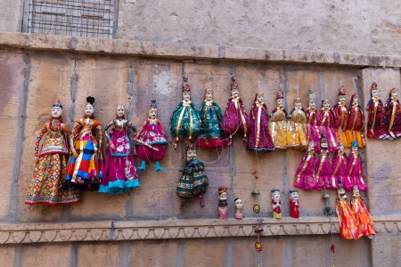 Photo for Jaisalmer, Rajasthan, India - 16 th October 2019 : Traditional Rajasthani Raja Rani dolls hanging from wall for sale near Patwon Ki Haveli. These are favourite for trourists travelling Jaisalmer. - Royalty Free Image