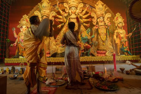 Photo for Howrah, West Bengal, India - 3rd October, 2022 : Hindu Priests worshipping Goddess Durga with shaari, traditional Bengali womens dress. Ashtami puja aarati - Durga Puja ritual- festival of Hinduism. - Royalty Free Image