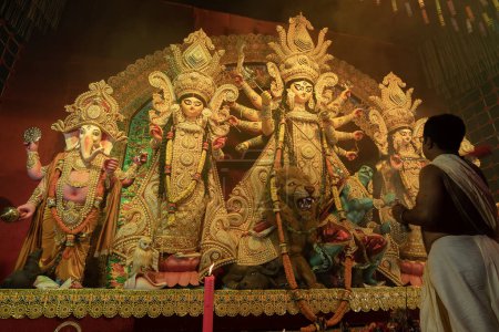Téléchargez les photos : Howrah, Bengale occidental, Inde - 3 octobre 2022 : Prêtres hindous vénérant la déesse Durga avec le shaari, robe traditionnelle des femmes bengali. Ashtami puja aarati - Durga Puja rituel- festival de l'hindouisme. - en image libre de droit