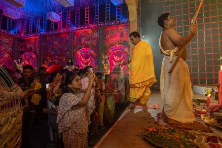 Photo for Howrah, West Bengal, India - 3rd October, 2022 : Beautiful girl child taking picture of Goddess Durga, inside Durga Puja pandal. Ashtami puja at night. Biggest fetsival of Hinduism. UNESCO heritage. - Royalty Free Image