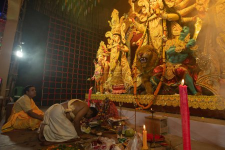 Photo for Howrah,West Bengal,India- 3rd October, 2022 : Hindu Priest showing respect, praying and worshipping Goddess Durga, kneels down position. Puja Pandal. Durga puja is unesco intangible cultural heritage. - Royalty Free Image