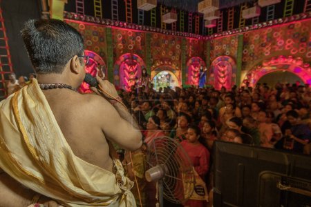 Photo for Howrah,West Bengal,India- 3rd October, 2022 : Hindu purohit uttering Sanskrit shlokas, guiding devotees for pushpanjali for praying and worshipping Goddess Durga, inside decorated Durga Puja Pandal. - Royalty Free Image