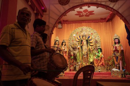Foto de Howrah, Bengala Occidental, India - 3 de octubre de 2022: Dhaakis jugando dhaaks para adorar a la Diosa Durga. Un ritual sagrado de Durga Puja. pandal decorado para la diosa Durga, el mayor festival del hinduismo. - Imagen libre de derechos