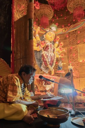 Téléchargez les photos : Howrah, Bengale Occidental, Inde- 3 Octobre, 2022 : Saint Hindou Shlokas de Bhagavad Gita est prononcé pour entendre tous les dévots à l'intérieur de Durga puja pandal.Durga Puja est le plus grand festival de l'hindouisme. - en image libre de droit