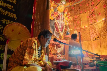 Téléchargez les photos : Howrah, Bengale Occidental, Inde- 3 Octobre, 2022 : Saint Hindou Shlokas de Bhagavad Gita est prononcé pour entendre tous les dévots à l'intérieur de Durga puja pandal.Durga Puja est le plus grand festival de l'hindouisme. - en image libre de droit