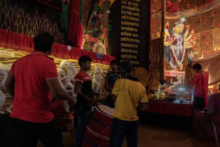Téléchargez les photos : Howrah, Bengale occidental, Inde - 3 octobre 2022 : Dhaakis jouant aux dhaaks pour adorer la déesse Durga. Un rituel sacré de Durga Puja. pandal décoré pour la déesse Durga, plus grand festival de l'hindouisme. - en image libre de droit