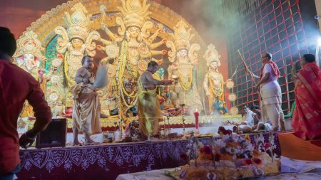 Téléchargez les photos : Howrah, Bengale Occidental, Inde - 5 octobre 2022 : Les Dhaakis jouent aux dhaaks pour adorer la Déesse Durga, tandis que la Déesse est offerte Vog, nourriture sainte et sucrée. Un rituel sacré Durga Puja à l'intérieur du pandal puja. - en image libre de droit