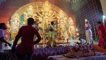 Téléchargez les photos : Howrah, Bengale Occidental, Inde - 5 Octobre, 2022 : Purohits hindous offrant Vog, nourriture douce sainte à la déesse Durga tandis que les Dhaakis jouent aux dhaaks, à l'intérieur de Durga puja pandal couvert de fumée sainte. - en image libre de droit