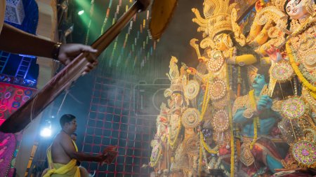 Photo for Howrah, West Bengal, India - 5th October, 2022 : Hindu Purohit worshipping Goddess Durga with Sari, traditional Hindu woman dress, inside Durga Puja pandal covered in Holy smoke. Durga Puja ritual. - Royalty Free Image