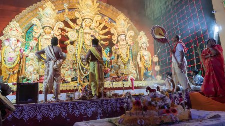 Photo for Howrah, West Bengal, India - 5th October 2022 : Dhaakis playing dhaaks for worshipping Goddess Durga, while Goddess is offered Vog, holy sweet food. A sacred Durga Puja ritual inside puja pandal. - Royalty Free Image