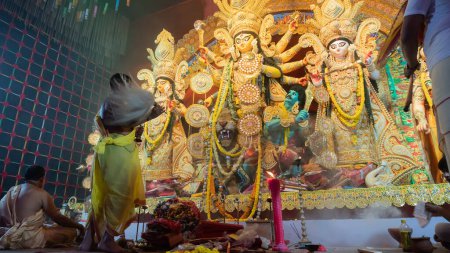 Téléchargez les photos : Howrah, Bengale occidental, Inde - 5 octobre 2022 : Prêtre hindou adorant la déesse Durga avec chamor, éventail de mouches. Ashtami puja aarati la nuit. Durga puja est patrimoine culturel immatériel de l'Unesco. - en image libre de droit