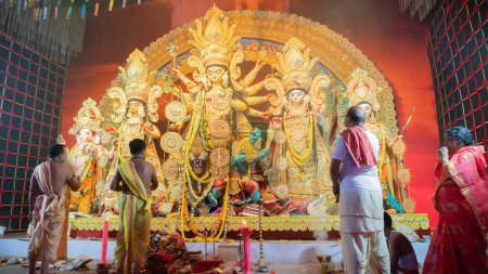 Foto de Howrah, Bengala Occidental, India - 5 de octubre de 2022: Purohits hindúes adoran a la Diosa Durga, devota con gran abanico que la transmite dentro de Durga Puja pandal. Ritual de Durga Puja. Festival del Hinduismo. - Imagen libre de derechos