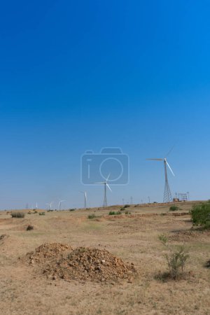 Photo for Blue desert sky and Electrical power generating wind mills producing alterative eco friendly green energy for consumption by local people.Thar desert,Rajasthan,India.Environment friendly power source. - Royalty Free Image