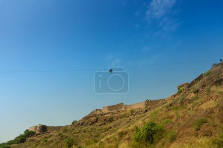 Zipline-Touristen fliegen über den Rao Jodha Desert Rock Park, Jodhpur, Rajasthan, Indien. In der Nähe des historischen Mehrangarh Fort, Park enthält ökologisch restaurierte Wüste und Land Vegetation, ein Touristenort.