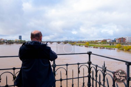 Photo for Badajoz, Spain, 14/12/2022. A man photographing the flooding of the Guadiana River in Badajoz covering parks and premises - Royalty Free Image