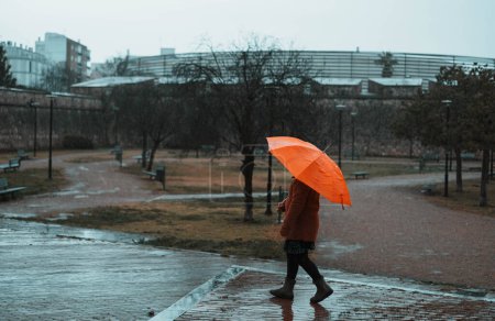 Petite fille marchant dans le parc un jour de pluie
