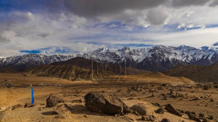 A wide-angle view of the snow covered mountain ranges with dark clouds in the horizon