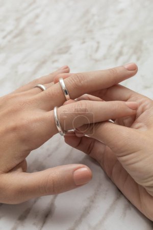 Foto de Estilo de vida glamoroso, poniendo en su mano anillos de plata en el estudio, hermosas joyas, objetos como accesorios, detalle de manicura - Imagen libre de derechos