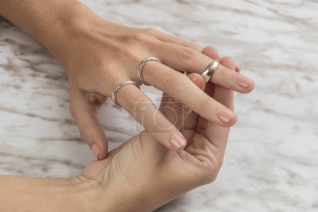 Foto de Colocación de anillos de plata en la mano en el estudio, hermosas joyas, objetos como accesorios, detalle de manicura - Imagen libre de derechos