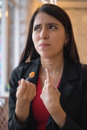 Foto de Degustación de alimentos, mujer latina joven con el pelo largo con expresión preocupada tratando de identificar los sabores, estilo de vida y alimentos - Imagen libre de derechos