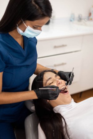 Foto de Odontóloga joven que realiza tratamiento dental, jornada laboral y profesión sanitaria, paciente femenina - Imagen libre de derechos